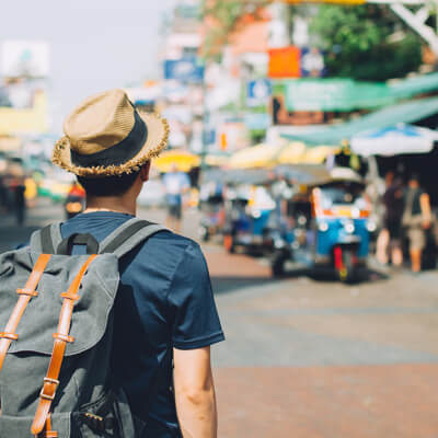 Young solo male wearing a backpack looking at an Asian market