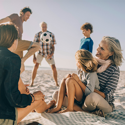 Family playing on the beach with their grandparents